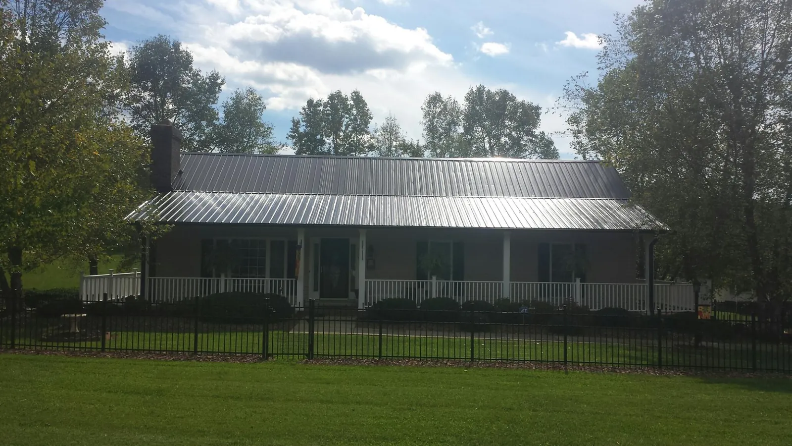 Gray metal roof on a brick ranch with a full width front porch — Gutter Guard Installation work by our crew in Douglas